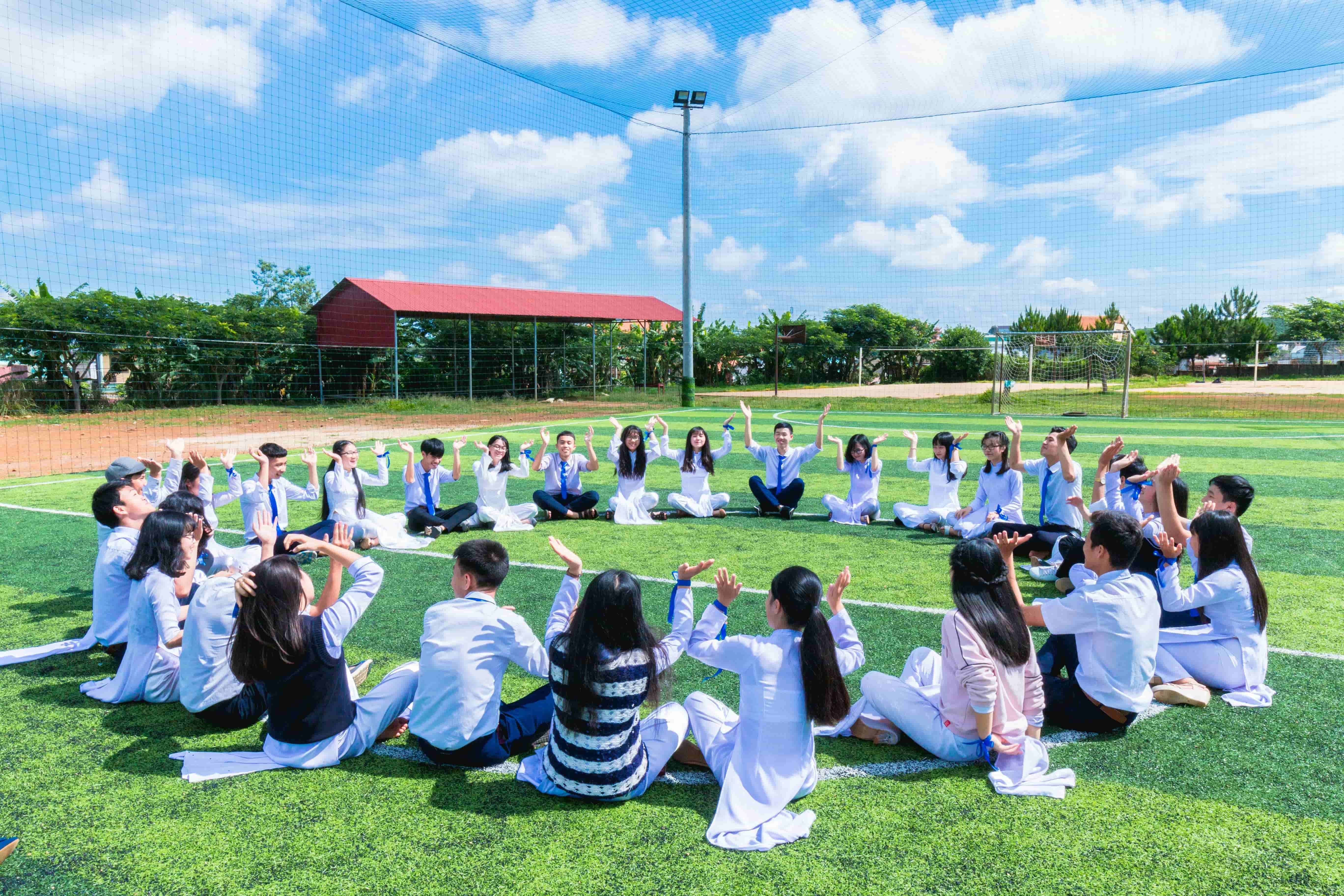 Students sitting in a circle in the center of a green field